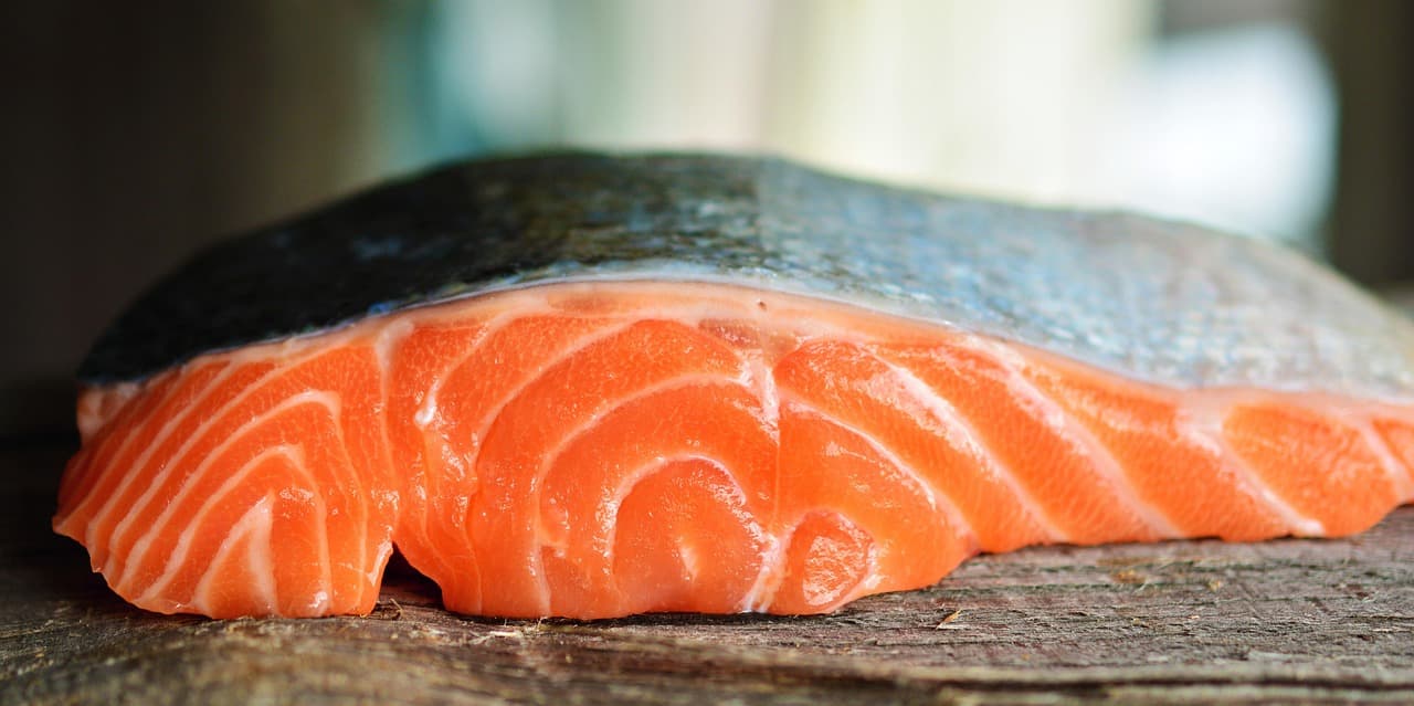 Hình ảnh minh họa: Biểu đồ so sánh hàm lượng omega-3 và protein giữa cá hồi hoang dã và cá hồi nuôi, kết hợp hình ảnh thịt cá hồi tươi ngon.