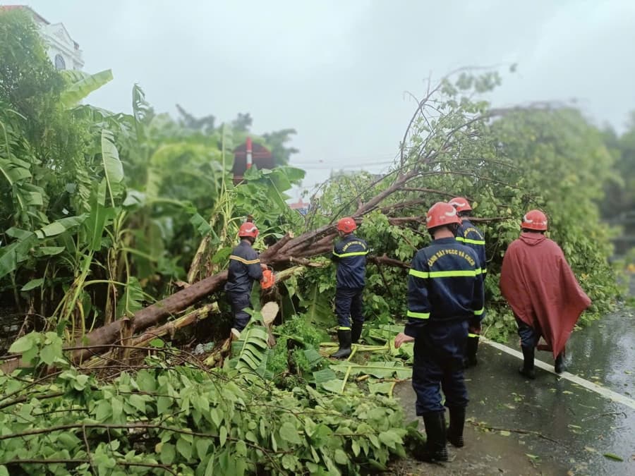 A group of people in Hai Phong cleaning up their homes after a typhoon, with receding floodwaters and rescue teams helping out.